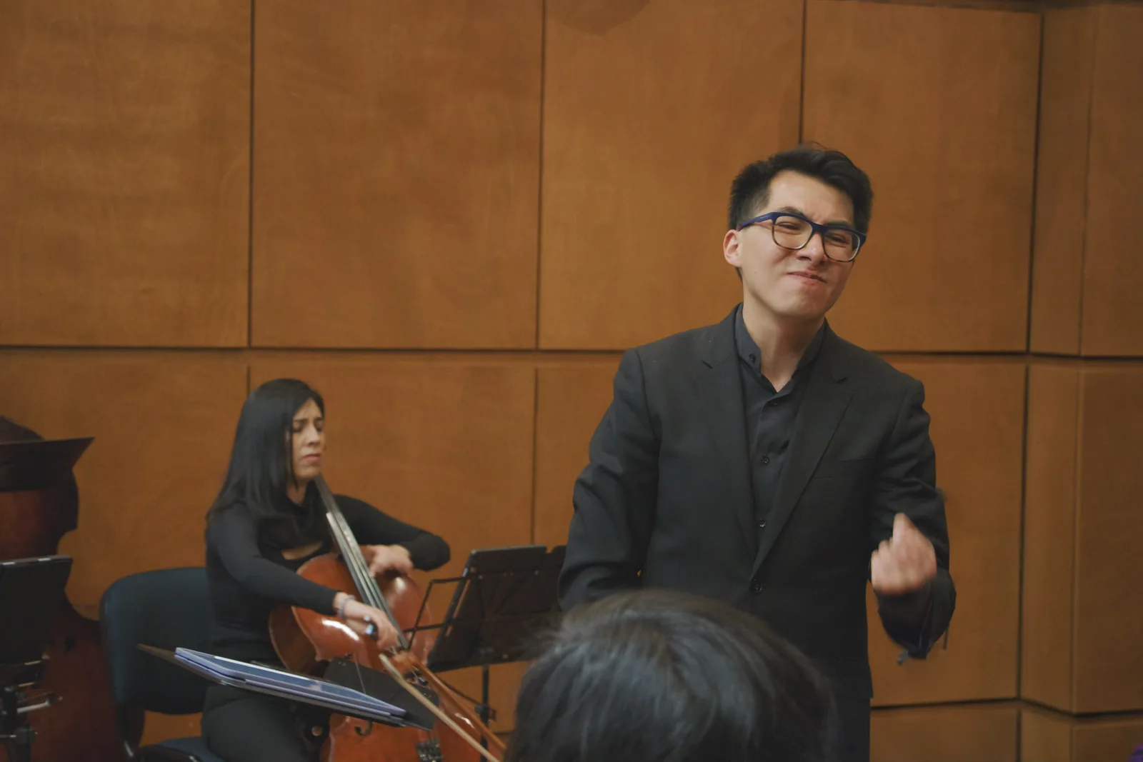 Andrés conducting a chamber ensemble in rehearsal, with a cellist playing beside him.